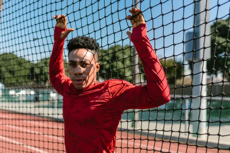Pub 1984 Apple : le spot qui a failli ne jamais passer An athlete in red sportswear leans on a net on an outdoor track.
