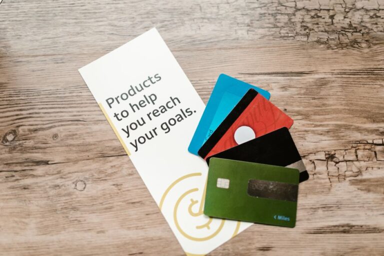 Apple Card : JPMorgan provisionne 2,2 milliards au T4 2025 Assorted credit cards on a wooden table next to a leaflet with motivational text about financial goals.