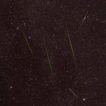 Bright meteors streak across a starry night sky during a captivating shower.