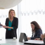 Businesswoman presenting data during an indoor corporate meeting.