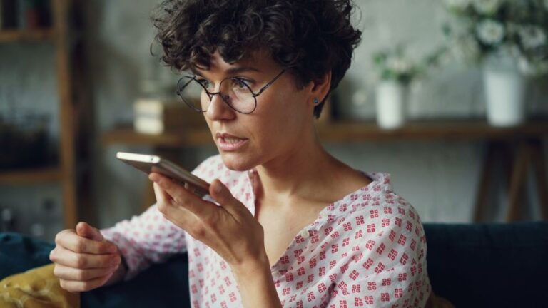 Gemini aide Apple à muscler Siri en 2026, sans prendre le volant Casual woman using voice command on smartphone at home.