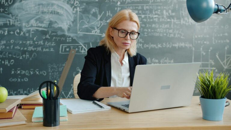 E-learning : créer des modules de formation avec une voix off générée par IA Woman working on a laptop in front of a chalkboard