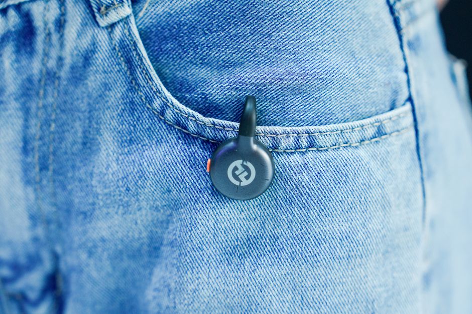 Close-up of a black Bluetooth tracker in a blue denim pocket, highlighting modern technology accessory design.