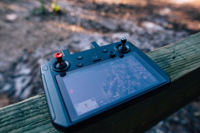 Vision Pro : le gros Pencil d’Apple veut dessiner dans l’air Close-up of a drone controller with visible screen, resting on a wooden surface outdoors.