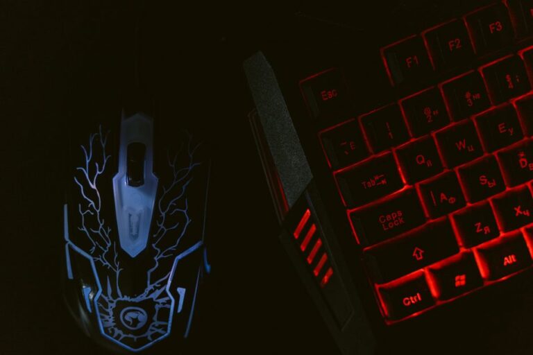 Corsair Galleon 100 SD : le Stream Deck prend le large Close-up of a glowing gaming mouse and a backlit keyboard in a dim setting, showcasing a tech-savvy setup.