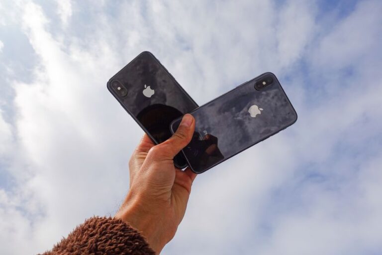iOS 26.3 bêta 2 arrive le 12 janvier 2026 : Android entrouvre la porte Close-up of a hand holding two smartphones against a cloudy sky, showcasing modern technology.