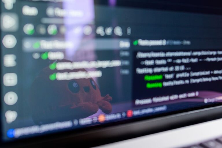 iOS 27 et macOS 27 : Rave et Fizz, le flou en plus Close-up of a laptop screen displaying programming code with a cute plush toy reflecting.