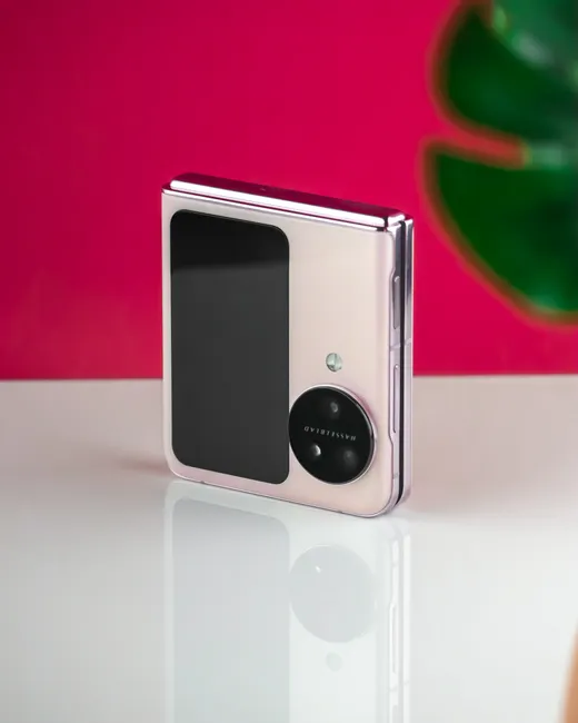 Close-up of a luxury foldable smartphone with a sleek design against a vibrant pink background.