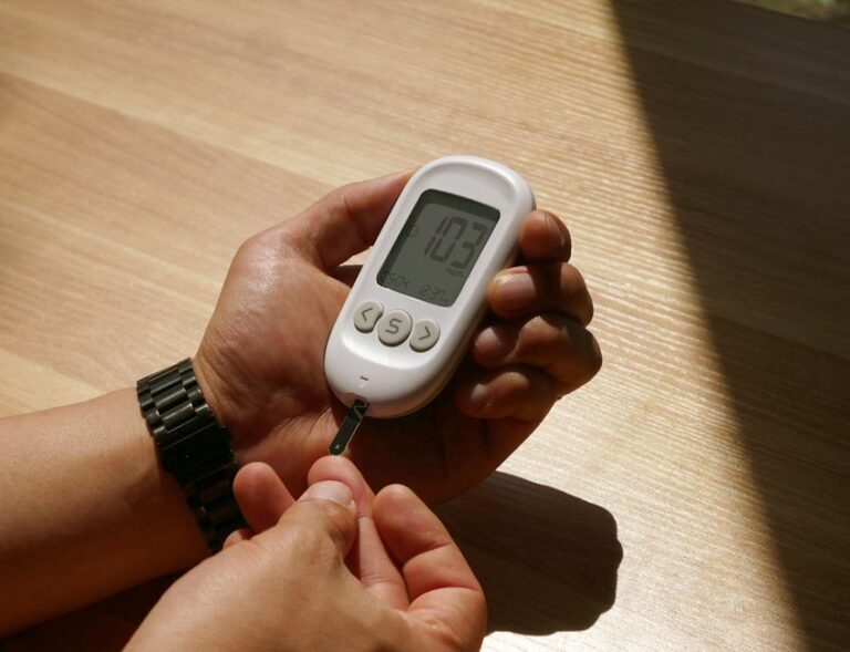 Instagram janvier 2026 : le faux reset qui rebondit vers Apple Close-up of a person checking blood glucose level with a meter in a sunny room, hands visible.