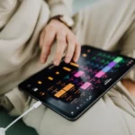 Gemini chez Apple, Pixelmator Pro sur iPad : le jardin s'agrandit Close-up of a person using a touchscreen tablet with a colorful interface indoors.
