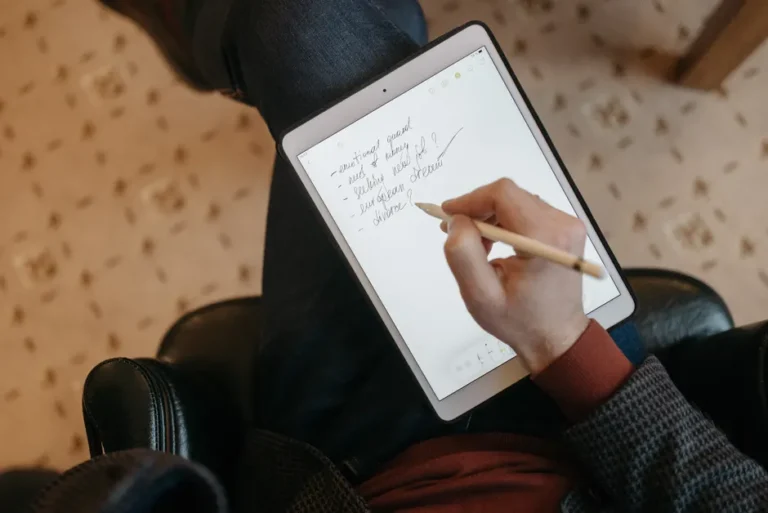 Apple Home : l’ancienne architecture ferme boutique le 10 février 2026 Close-up of a person writing on a tablet with a stylus in a cozy indoor environment.