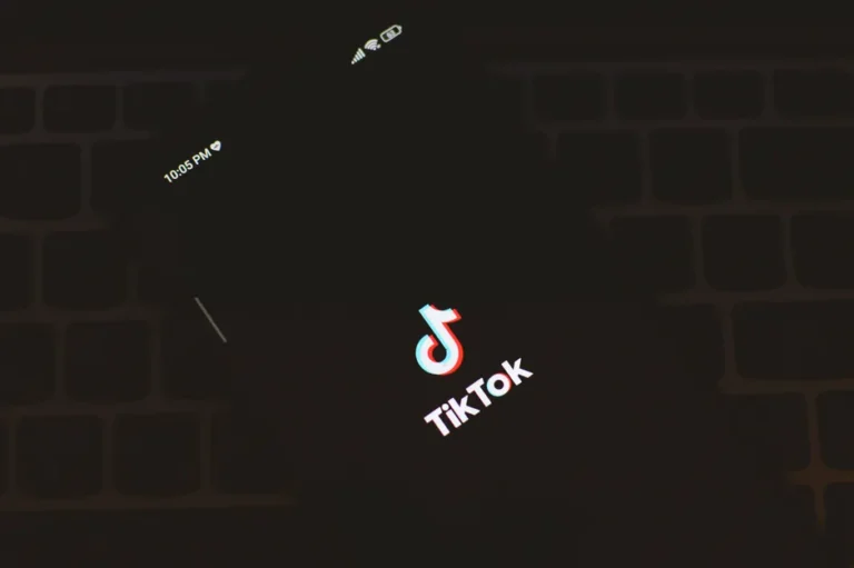 Close-up of a smartphone displaying the TikTok app logo against a dark keyboard background.