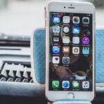 iPhone 18 : Dynamic Island réduite en 2026, bordures inchangées Close-up of a smartphone mounted on a car dashboard showing home screen with apps.