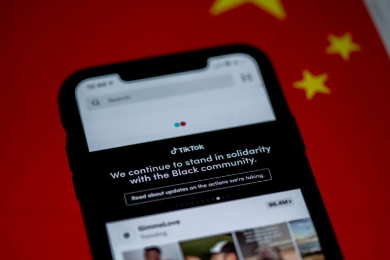 TikTok américain en panne le 25 janvier 2026 : le propriétaire change, les doutes restent Close-up of a smartphone with TikTok app displayed against a China flag backdrop, highlighting solidarity message.