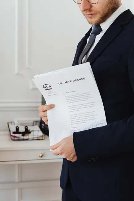 Close-up of a suited professional holding a divorce decree document indoors.