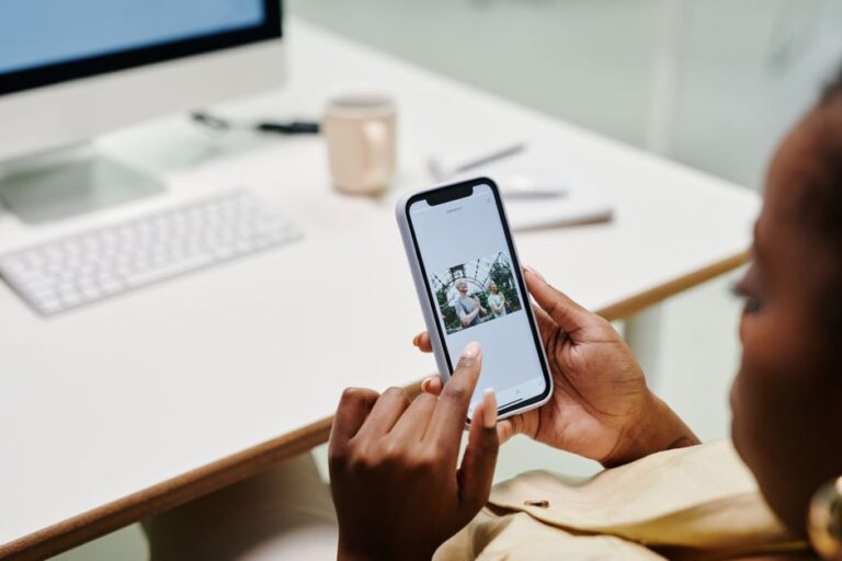 iOS 18.2 classe vos mails en quatre catégories, mais vous pouvez reprendre la main Close-up of hands using a smartphone at a desk with a computer. Ideal for tech and lifestyle content.