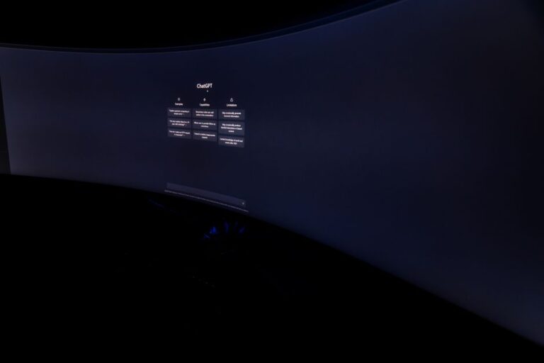 Dell UltraSharp 52 : 6K, 120 Hz et 2 899,99 dollars, le bureau XXL Curved monitor screen showing ChatGPT interface in low-light, focus on technology and AI.