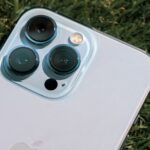 Detailed close-up of smartphone camera lenses on green grass background.