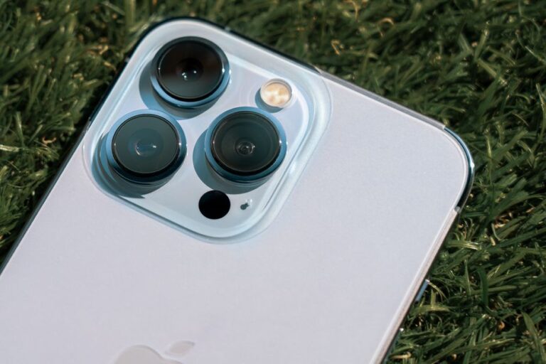 iPhone 200 MP : le téléobjectif Apple reste entre 2027 et 2028 Detailed close-up of smartphone camera lenses on green grass background.