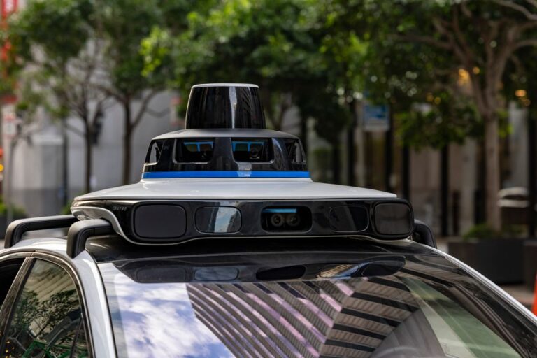 Apple Car : Airbnb confirme le projet autonome d’Apple en 2026, sans voiture au bout Detailed view of sensors atop an autonomous car, showcasing advanced technology in an urban setting.