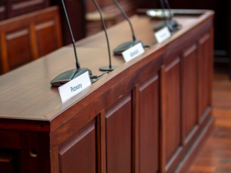 Epic paie 800 millions à Google sur six ans, sous contrôle du juge Empty courtroom desk with microphones and nameplates in a Polish court setting.