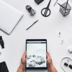 Apple Creator Studio à 12,99 $ : le double abonnement guette Flat lay of a modern workspace featuring a tablet, gadgets, and coffee for creative work.