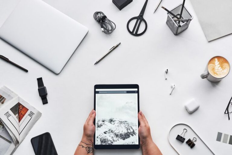 Apple Creator Studio à 12,99 $ : le double abonnement guette Flat lay of a modern workspace featuring a tablet, gadgets, and coffee for creative work.