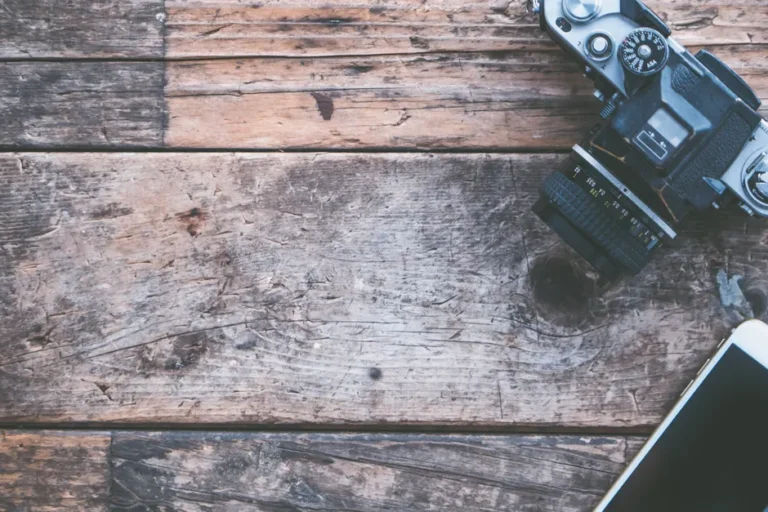 L’iPhone 4 revient sur TikTok en 2026, mais pas pour Internet Flat lay of vintage camera and smartphone on rustic wooden planks, perfect for creative projects.