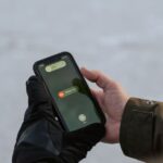 Panne Verizon du 14 janvier 2026 : des iPhone en SOS, iOS hors de cause Gloved hands holding a smartphone displaying an emergency SOS screen.