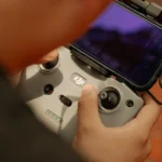 Hands using a modern drone controller with attached smartphone for scenic aerial views.