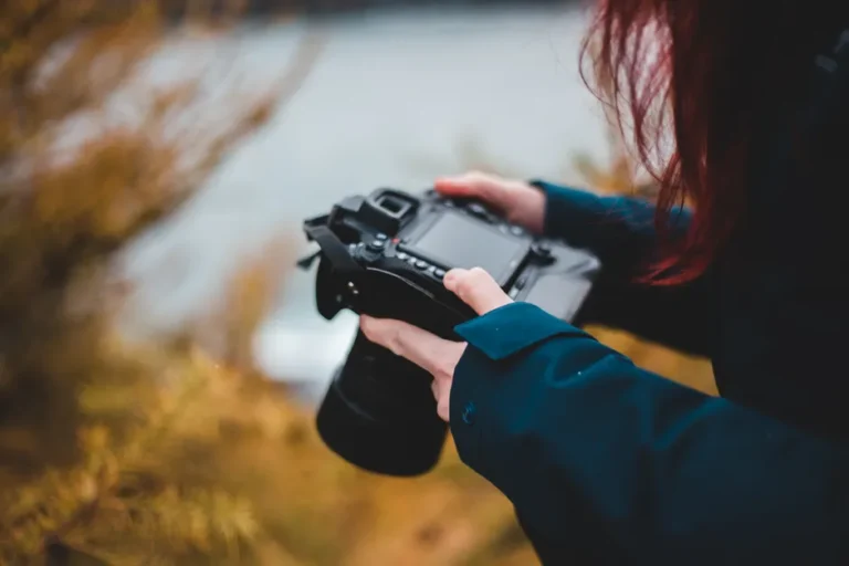Apple recadre l’image en janvier 2026 avec MANZANO et DeepMMSearch-R1 High angle of crop faceless female photographer in warm clothes watching pictures on professional digital camera while standing on grassy terrain near sea in autumn