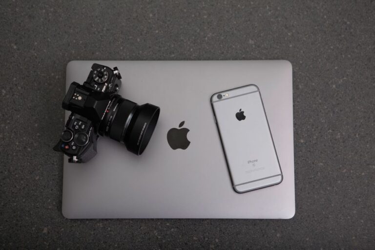 iPhone 18 Pro : un téléconvertisseur pour voir plus loin, avec la lumière en moins High-angle shot of DSLR camera, MacBook, and iPhone on textured surface, showcasing modern technology essentials.