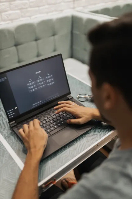 Man using a laptop with a technology interface screen in a modern setting.