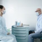 Apple Watch après ablation : 52,9 % de récidives détectées et moins d'hospitalisations Medical professional consults a senior patient, both wearing masks in a clinic setting.