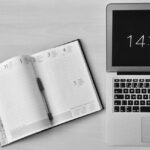 Minimalist office workspace with a notebook and MacBook Air showing 14:41 time.