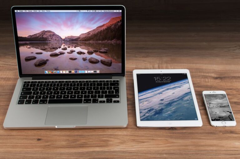 Bureau Apple en 2025 : l’iPad Pro au centre, le MacBook Air en joker Modern workspace showcasing Apple laptop, tablet, and smartphone on a wooden desk.