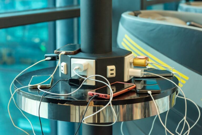 Jackery Explorer 1500 Ultra : 1 536 Wh, IP65 et 1 800 W, le courant passe Multiple smartphones charging at a public charging station indoors. USB and electric connections visible.