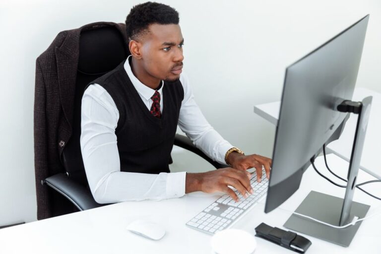 Apple Intelligence en 2026 : Federighi reprend la main, Gemini en renfort Professional man intensely working on a computer at his office desk, focused and determined in a business environment.