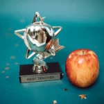 Silver star-shaped trophy with apple on a blue background for teacher appreciation.