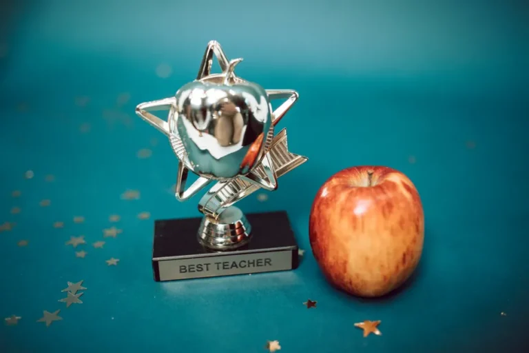 Apple TV décroche 7 prix aux Critics Choice Awards 2026 : The Studio en tête Silver star-shaped trophy with apple on a blue background for teacher appreciation.