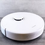 Sleek white robot vacuum cleaner on a wooden floor, perfect for smart home setups.