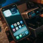 Anker Nano au CES 2026 : 45 W et dock 13-en-1, prix en baisse Smartphone and digital charging station on a desk with Klipsch speaker visible.