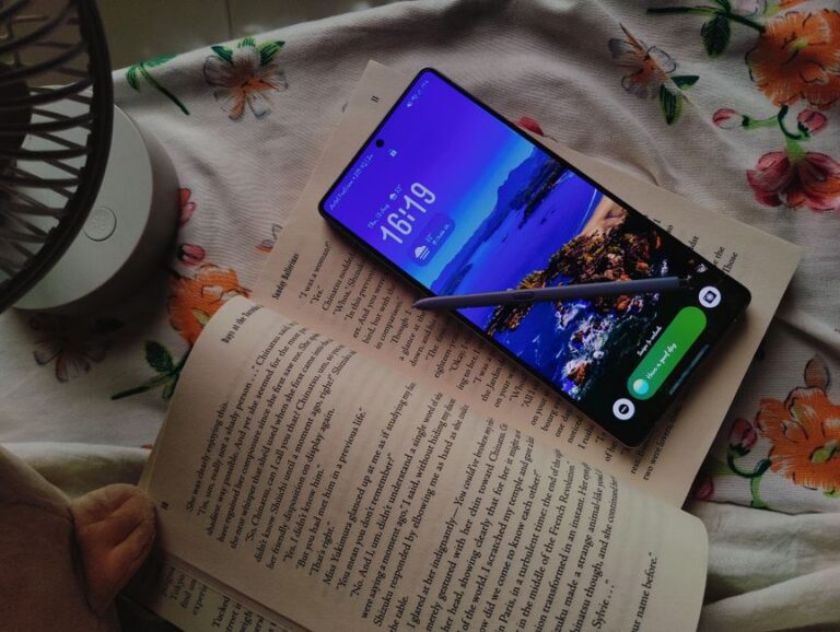 iPhone Fold 2026 : 7,8 pouces, 2 000 dollars et le pari du pli Smartphone displaying a scenic beach wallpaper atop an open book, illuminated by soft daylight.