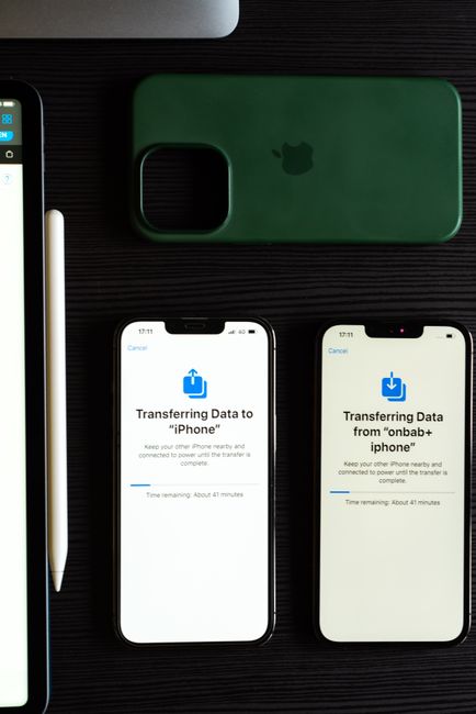 Two smartphones transferring data, showcasing modern mobile technology on a dark desk.