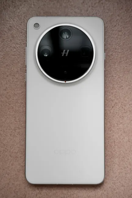White smartphone with circular camera design on a textured surface.