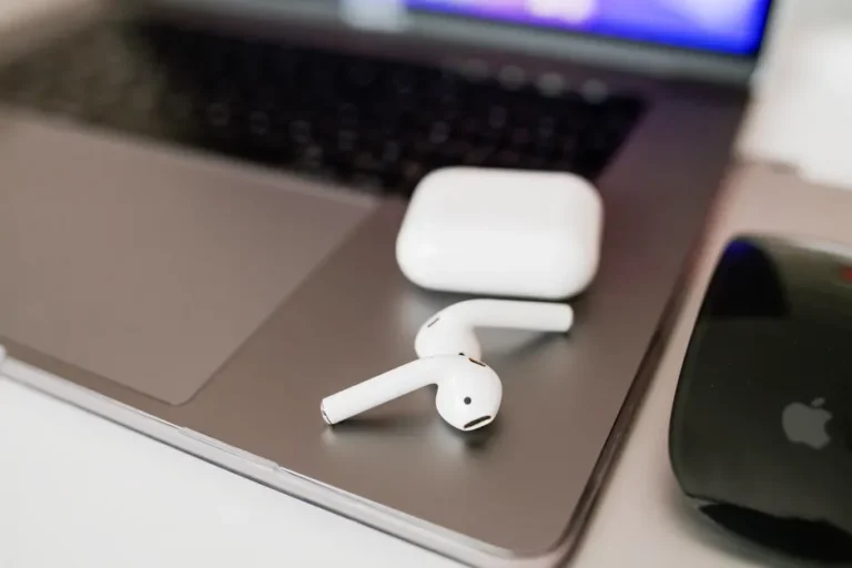 AirPods Pro 3 à 199,99 dollars : Amazon baisse la note White wireless earbuds and charging case on a sleek laptop close-up.