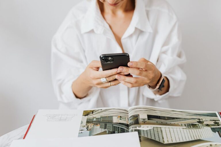 Le boomerang Halide revient chez Apple : Sebastiaan de With rejoint le design Woman in white shirt using smartphone while reading architecture magazine. Indoor setting.
